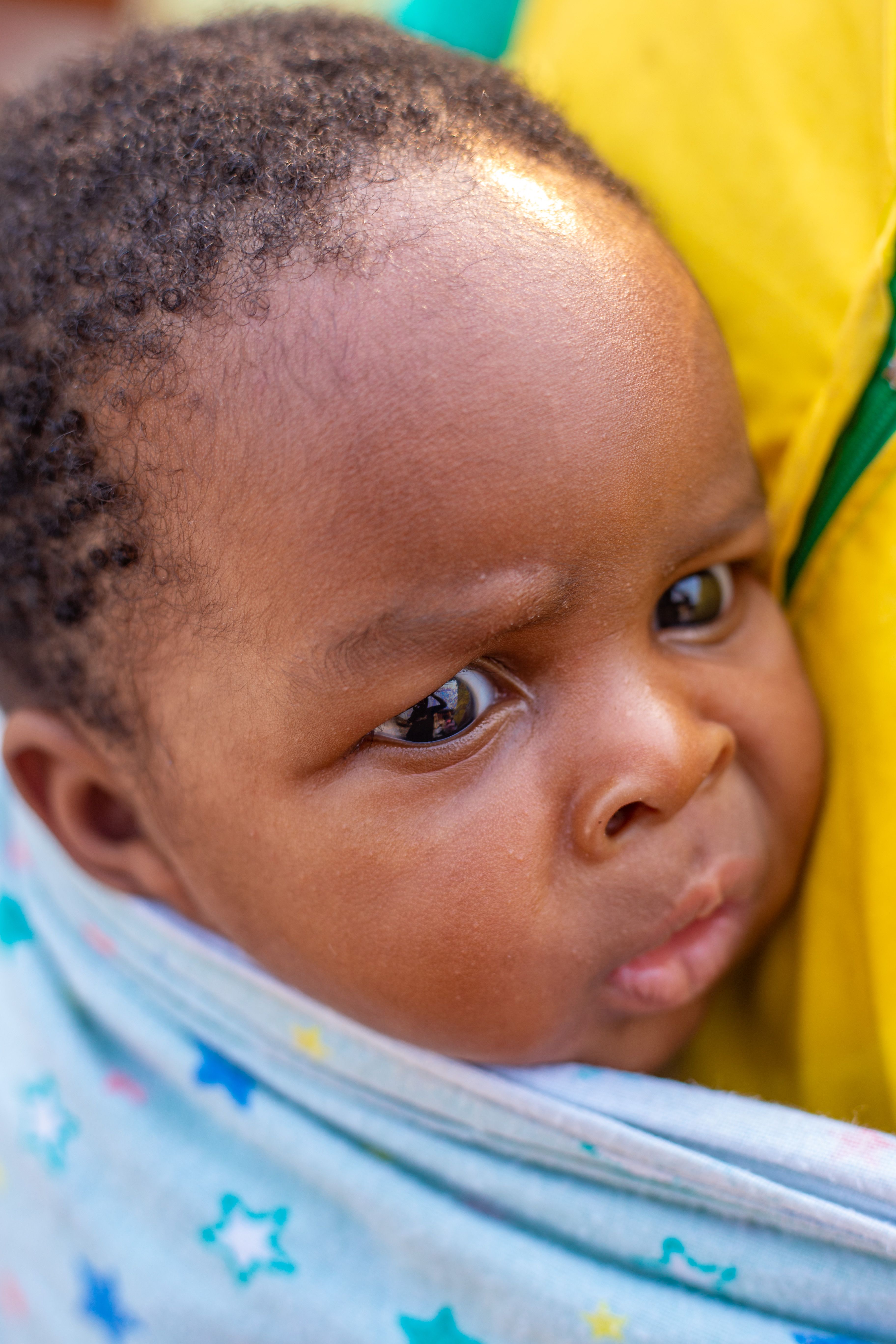 Adorable close-up of a baby curiously peeking from a colorful starry blanket.