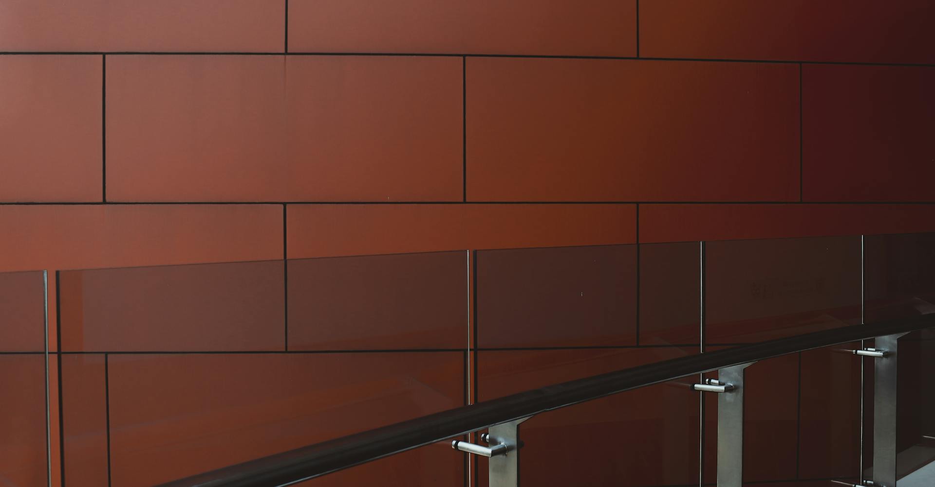 Modern interior wall with brown panels and sleek glass railing, showcasing contemporary design elements.