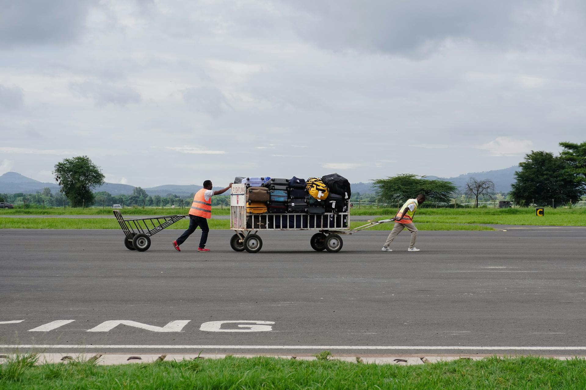 Men Towing Trailer with Baggage on Airport Tarmac