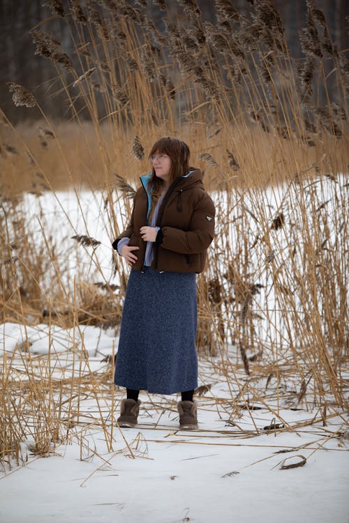 Woman in Jacket and Skirt Standing among Rushes in Winter