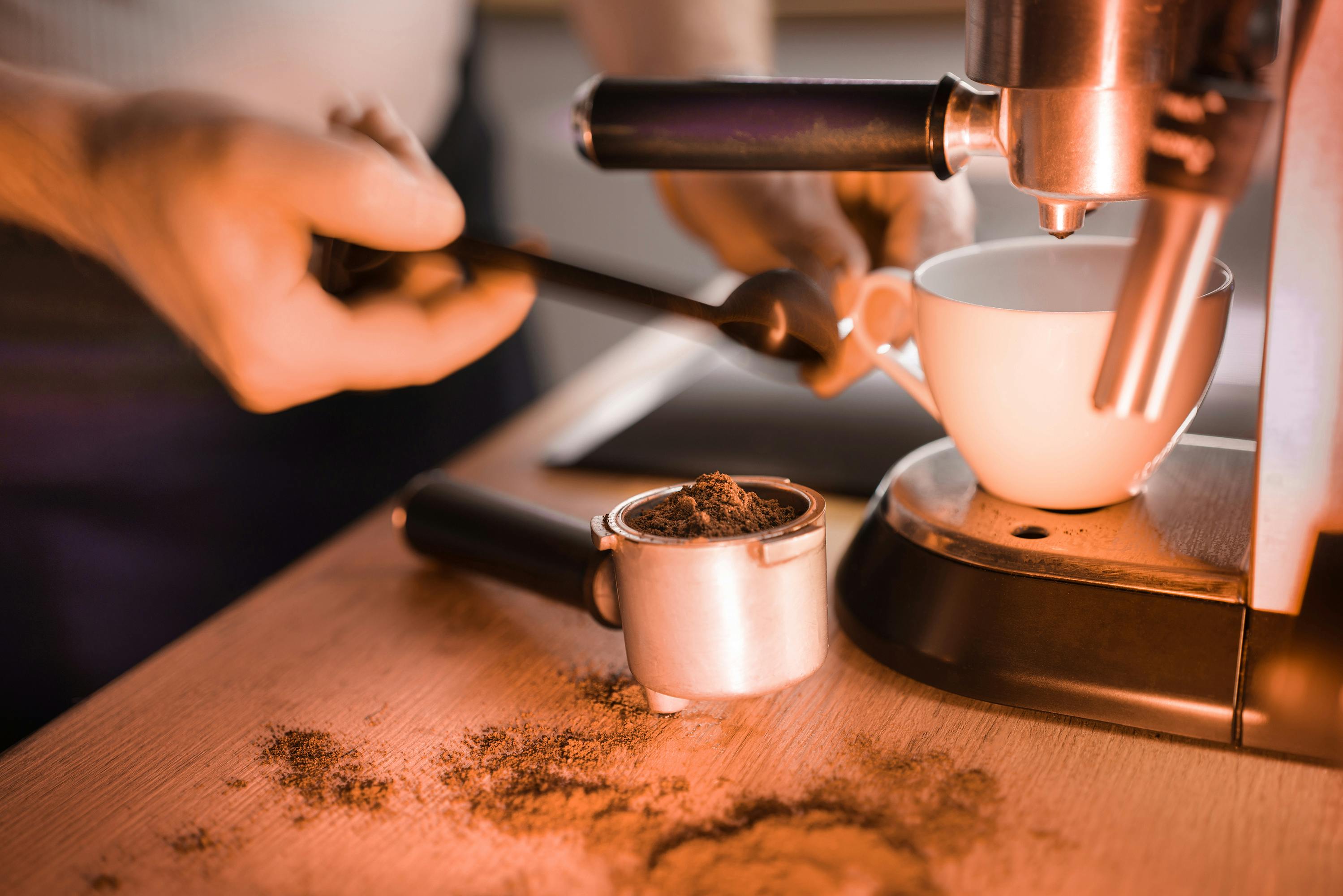 Close-up of a barista using an espresso machine to prepare coffee with fresh ground beans.