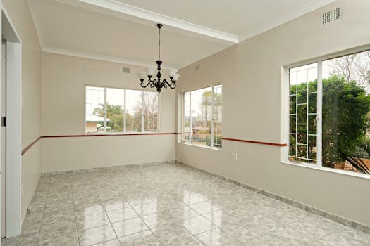 Spacious empty dining room with chandelier and large windows offering natural light.