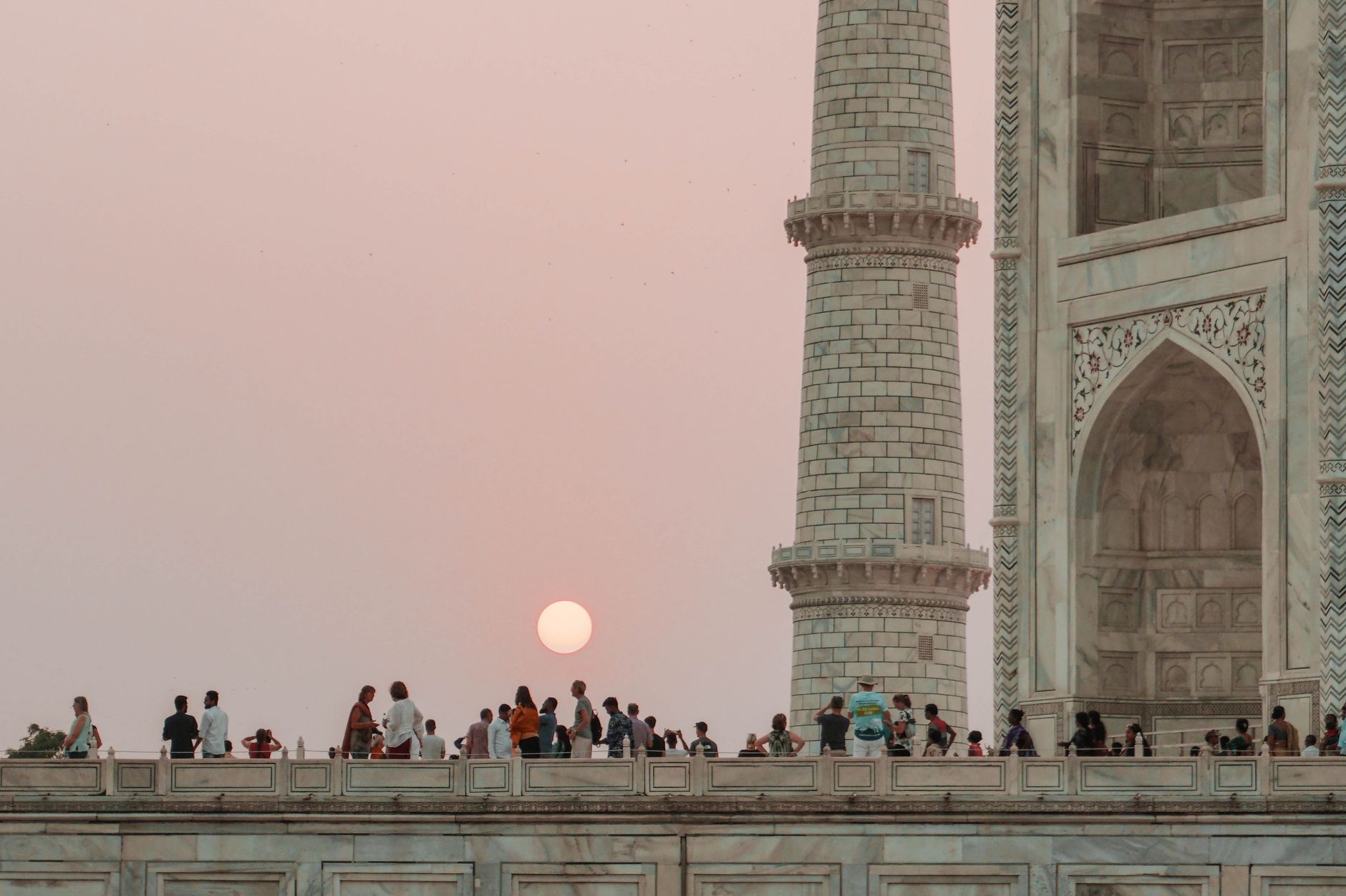 People watching a beautiful sunset at the iconic Taj Mahal, India.