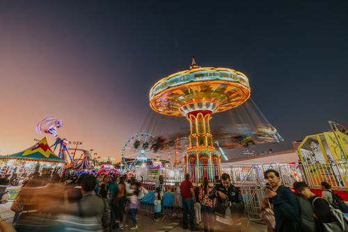 Free A bustling amusement park at night with colorful rides and a lively crowd, captured using long exposure photography. Stock Photo