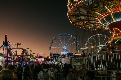 Free Experience the fun and excitement at a bustling amusement park during sunset, filled with colorful lights and vibrant rides. Stock Photo