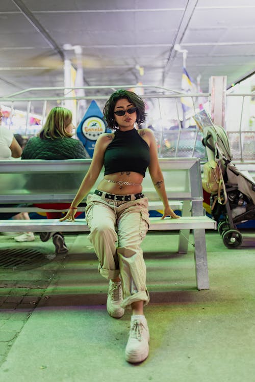 Model Wearing a Black Crop Top and Beige Pants Sitting on a Bench