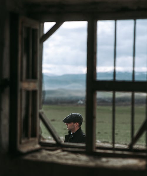 Man in a Flat Cap Outside the Window of a Country Cottage