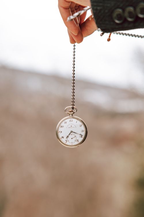 Free A classic pocket watch with chain held outside against a blurred background. Stock Photo
