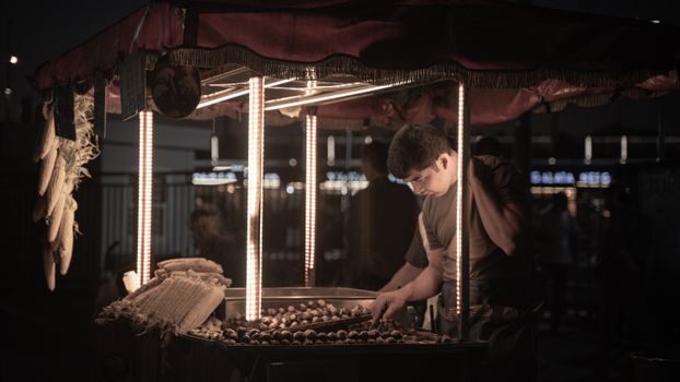 A street vendor in Fatih, İstanbul roasts chestnuts under a warm night glow, capturing the lively city atmosphere.