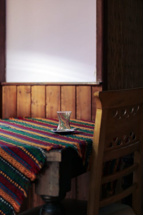 An Empty Glass Standing on a Table with a Colorful Tablecloth 