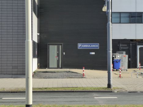 Ambulance parking area on a quiet street near a modern building with road access.