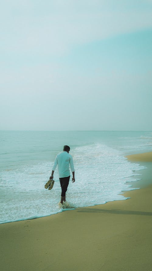 A man walking on the beach with a bag