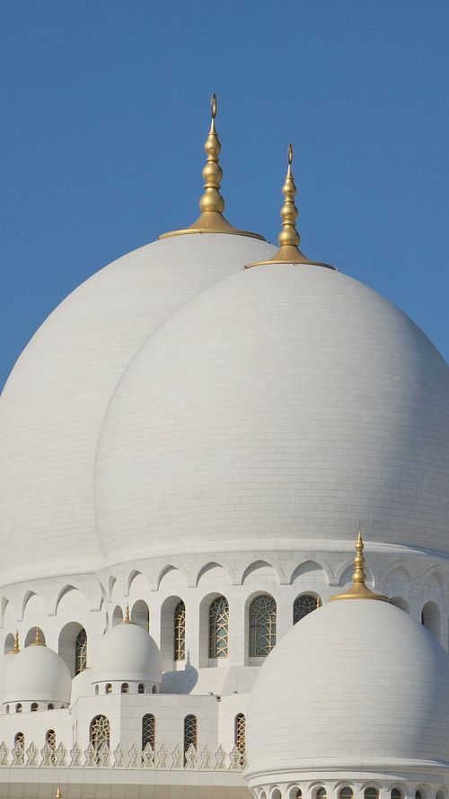 Free Close-up of the iconic white domes of Sheikh Zayed Grand Mosque in Abu Dhabi against a clear blue sky. Stock Photo