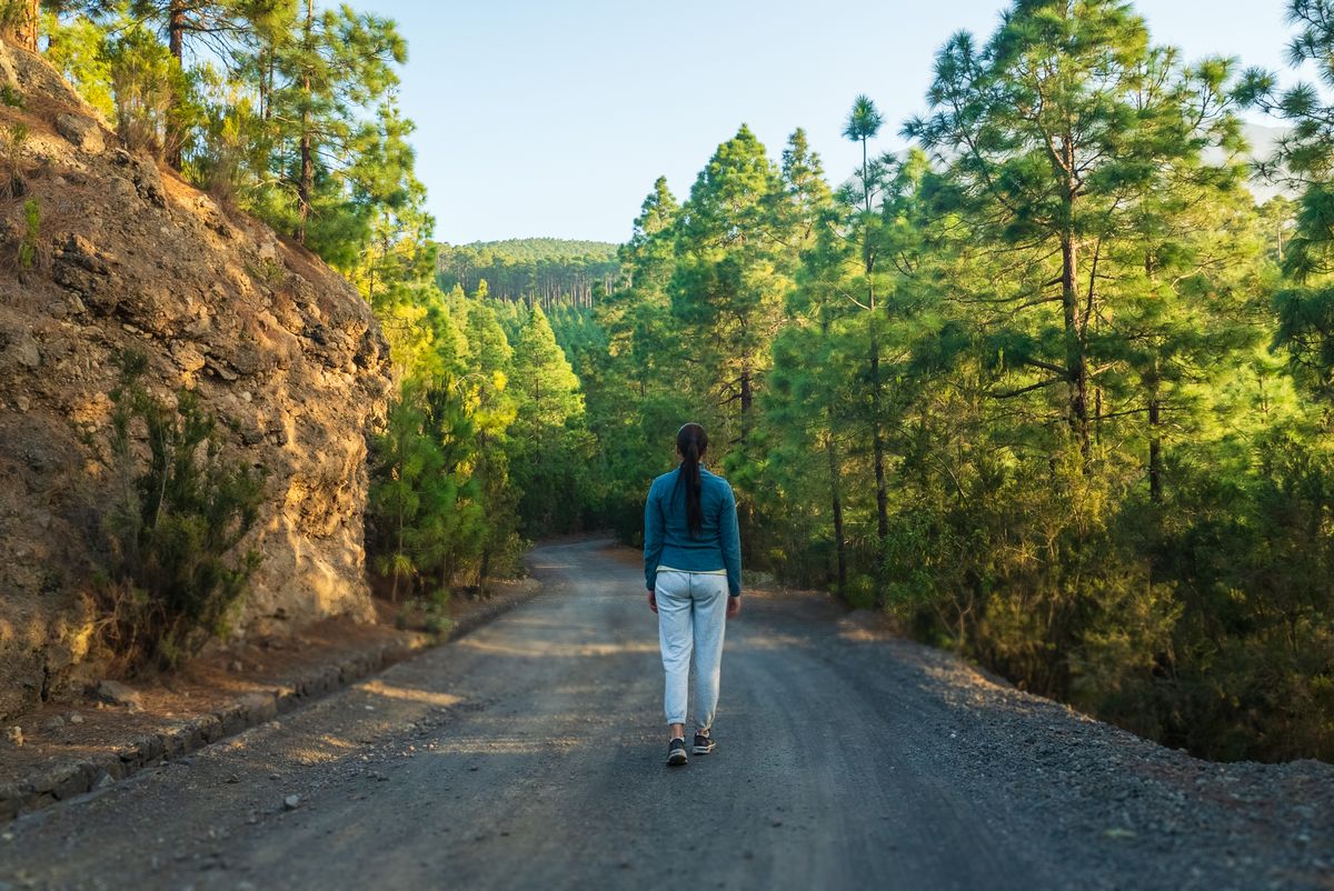 Mulher caminhando em trilha na natureza, hábito que ajuda a estabilizar a glicose