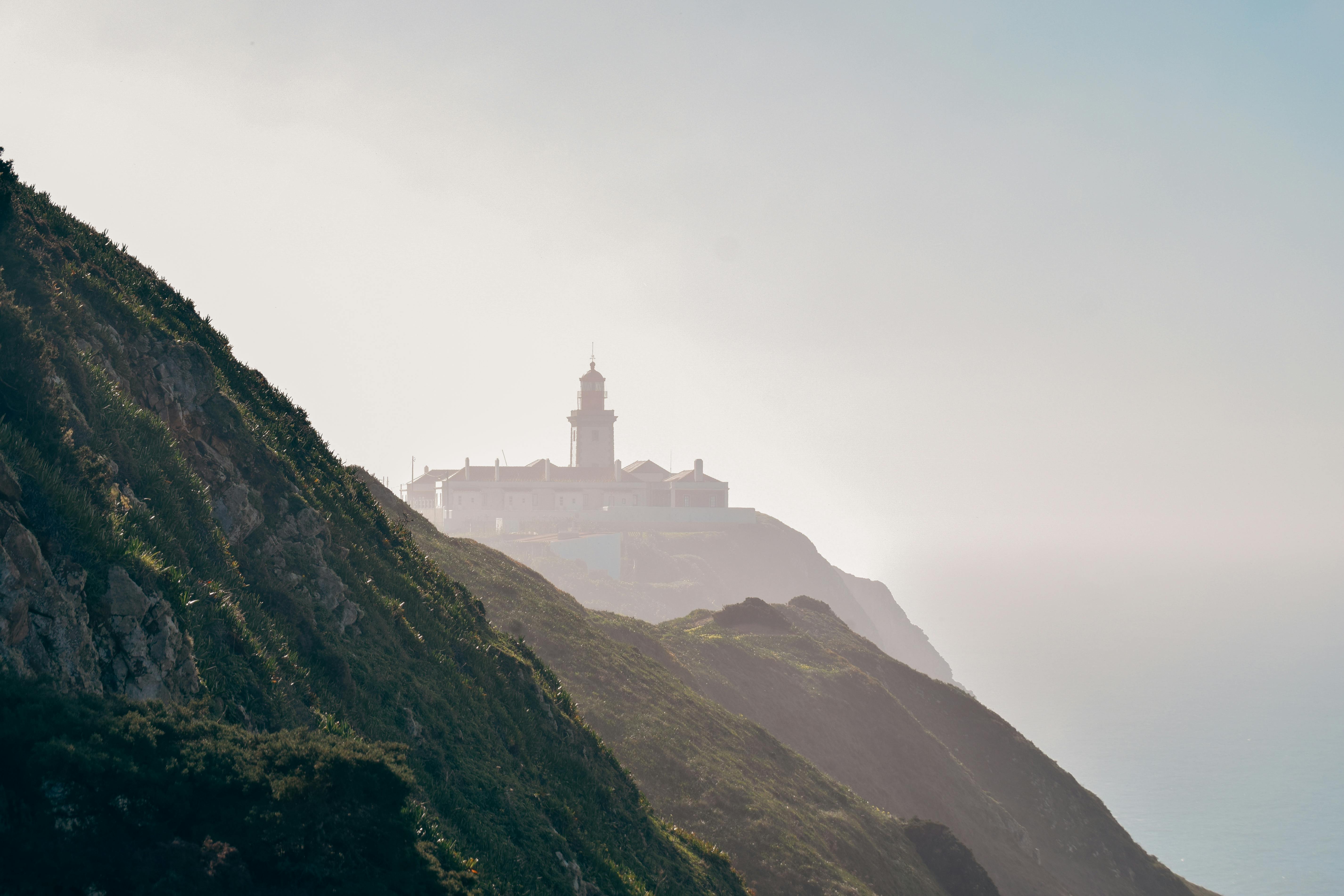 Scenic view of Cabo da Roca lighthouse shrouded in fog on a cliffside.