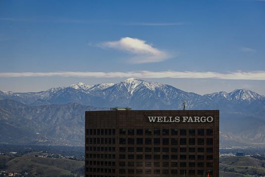 View of a Wells Fargo building with snow-capped mountains in the background under a clear blue sky.