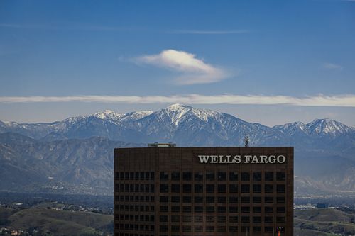 Free View of a Wells Fargo building with snow-capped mountains in the background under a clear blue sky. Stock Photo