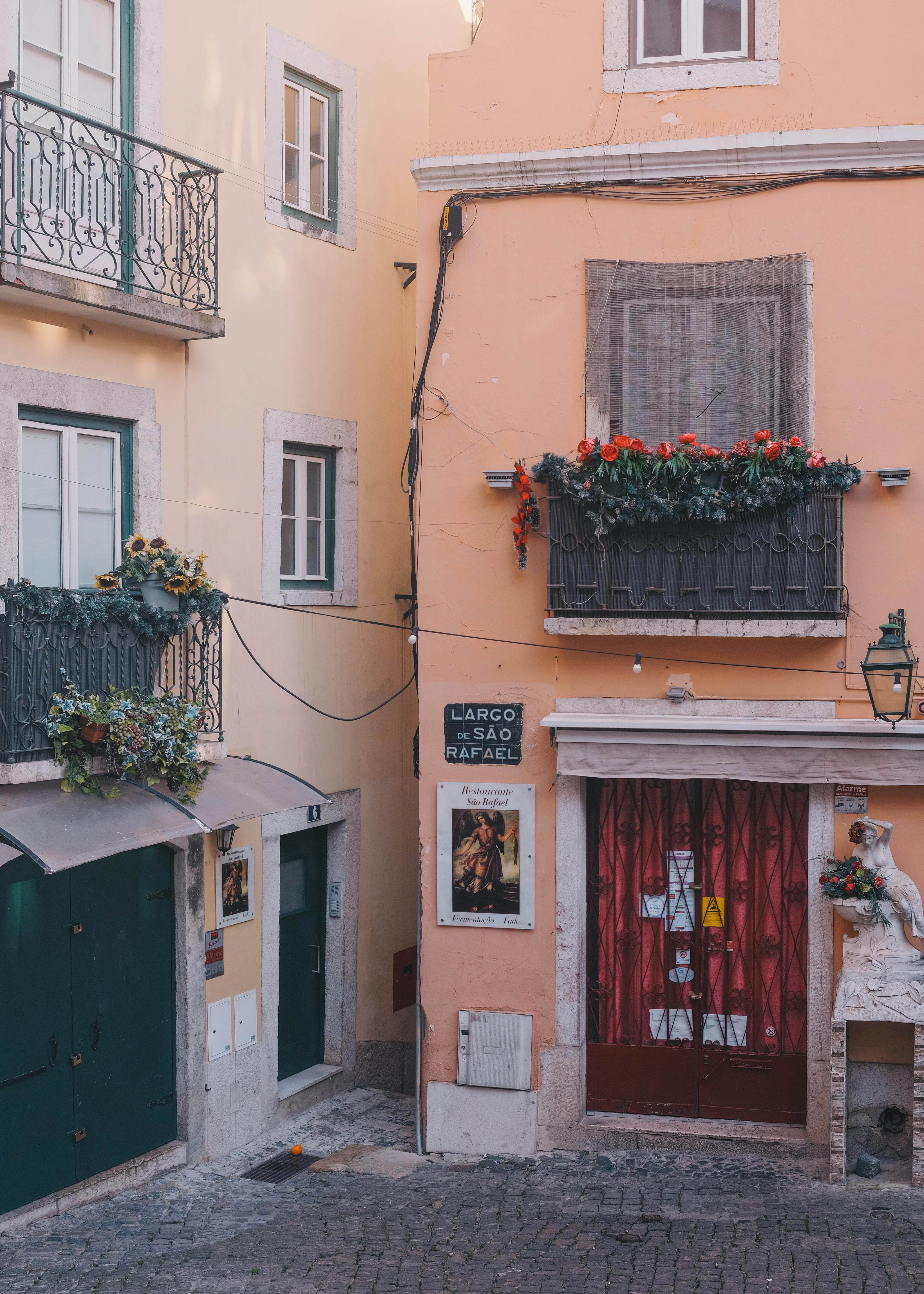 Capture of a picturesque street in Lisbon featuring colorful facades and floral balconies.