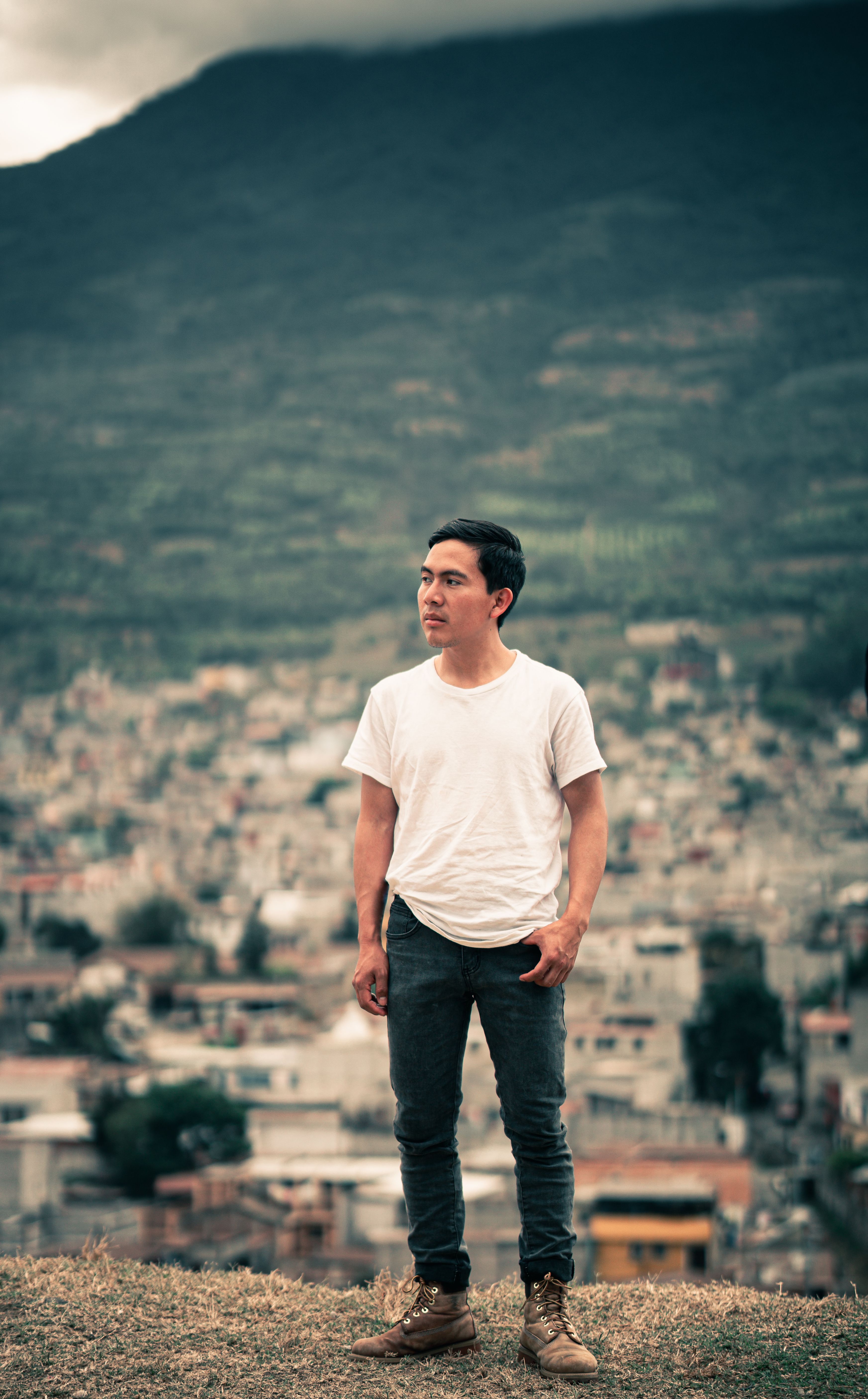 A man stands overlooking the cityscape of Antigua Guatemala with a mountainous background.