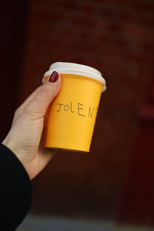 A person holding a cup with the word joe on it