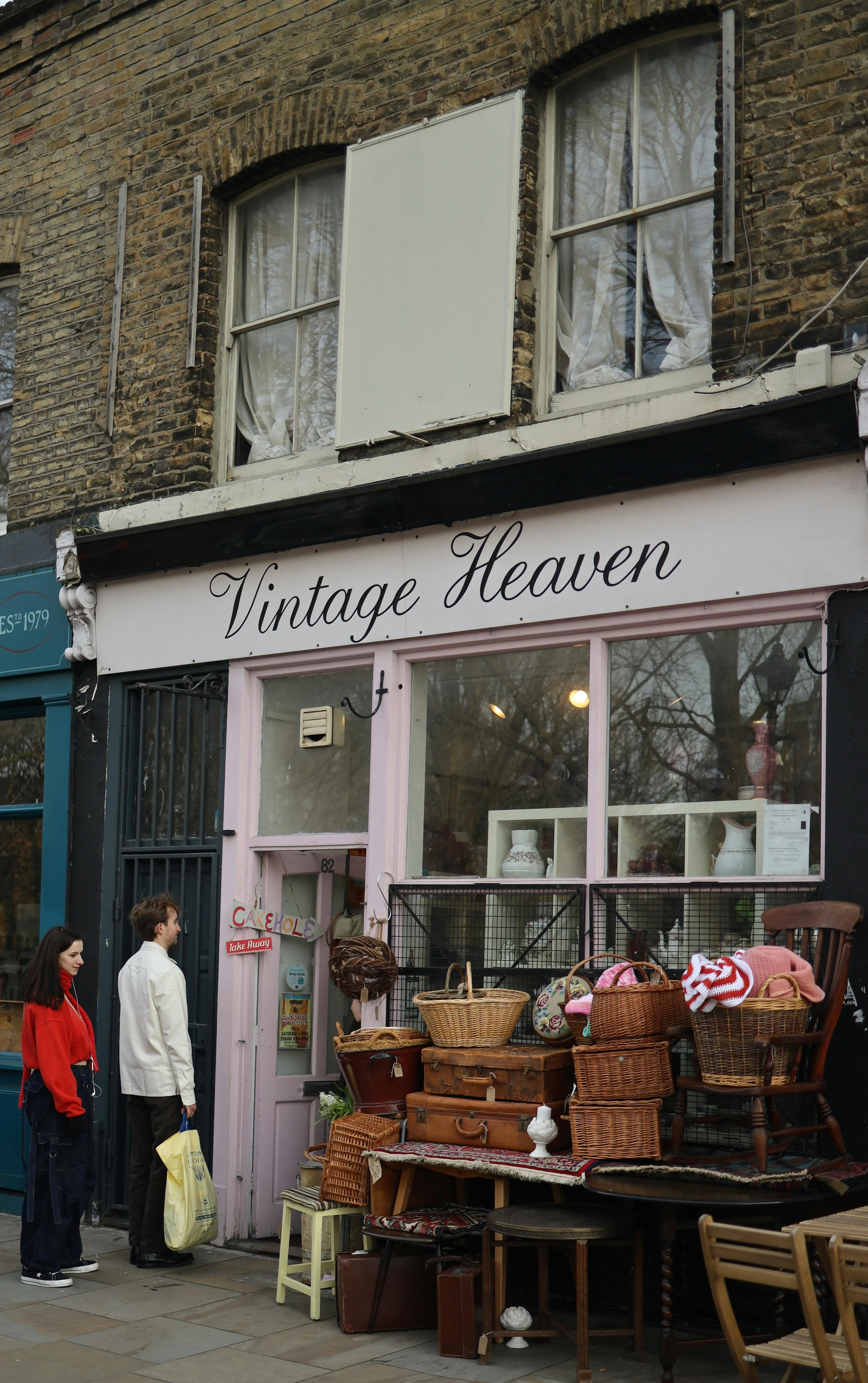 People exploring a vintage shop with wicker baskets on display outside in an urban setting.