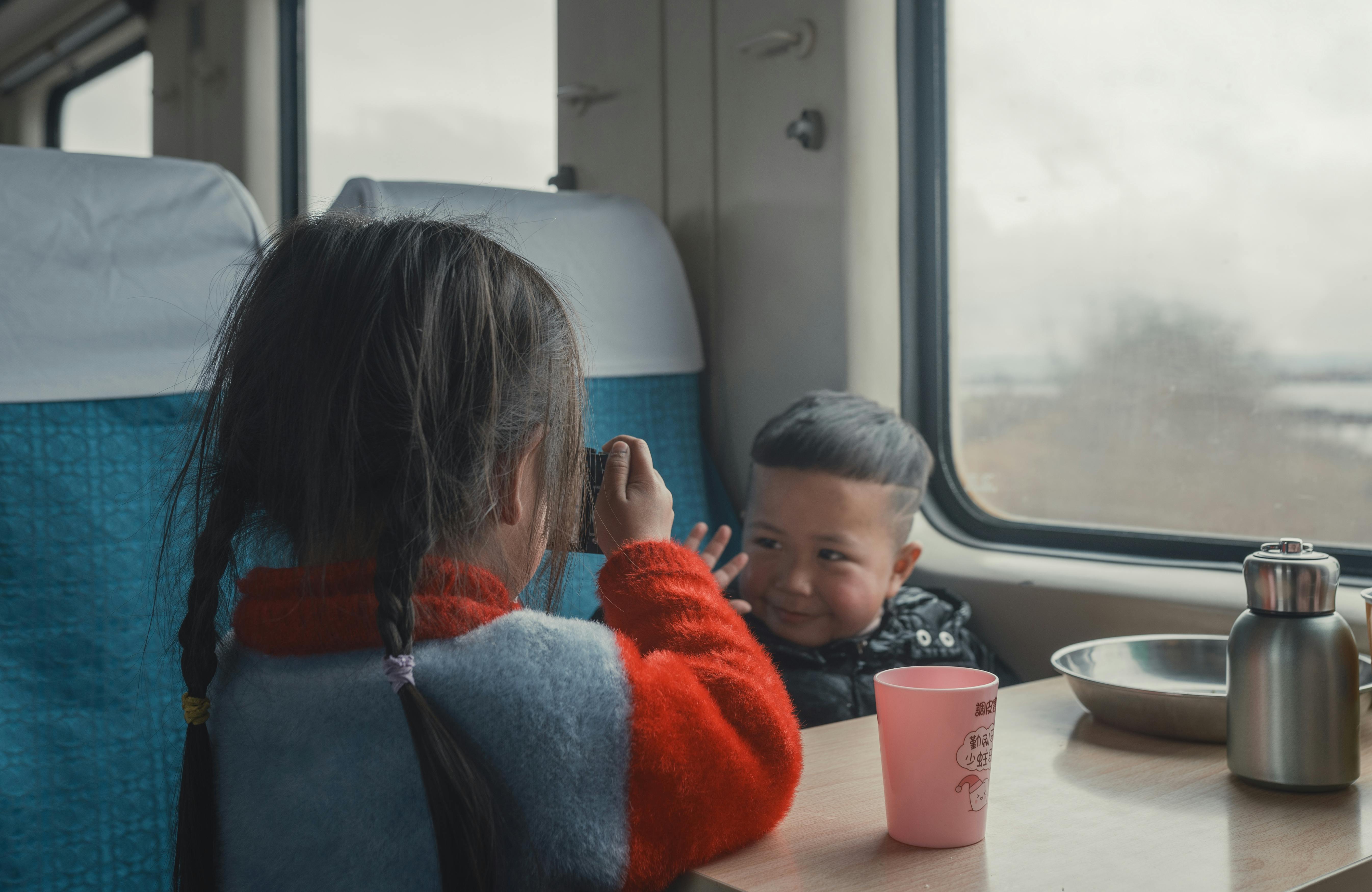 Two children playing inside a train cabin, capturing moments and enjoying the ride.