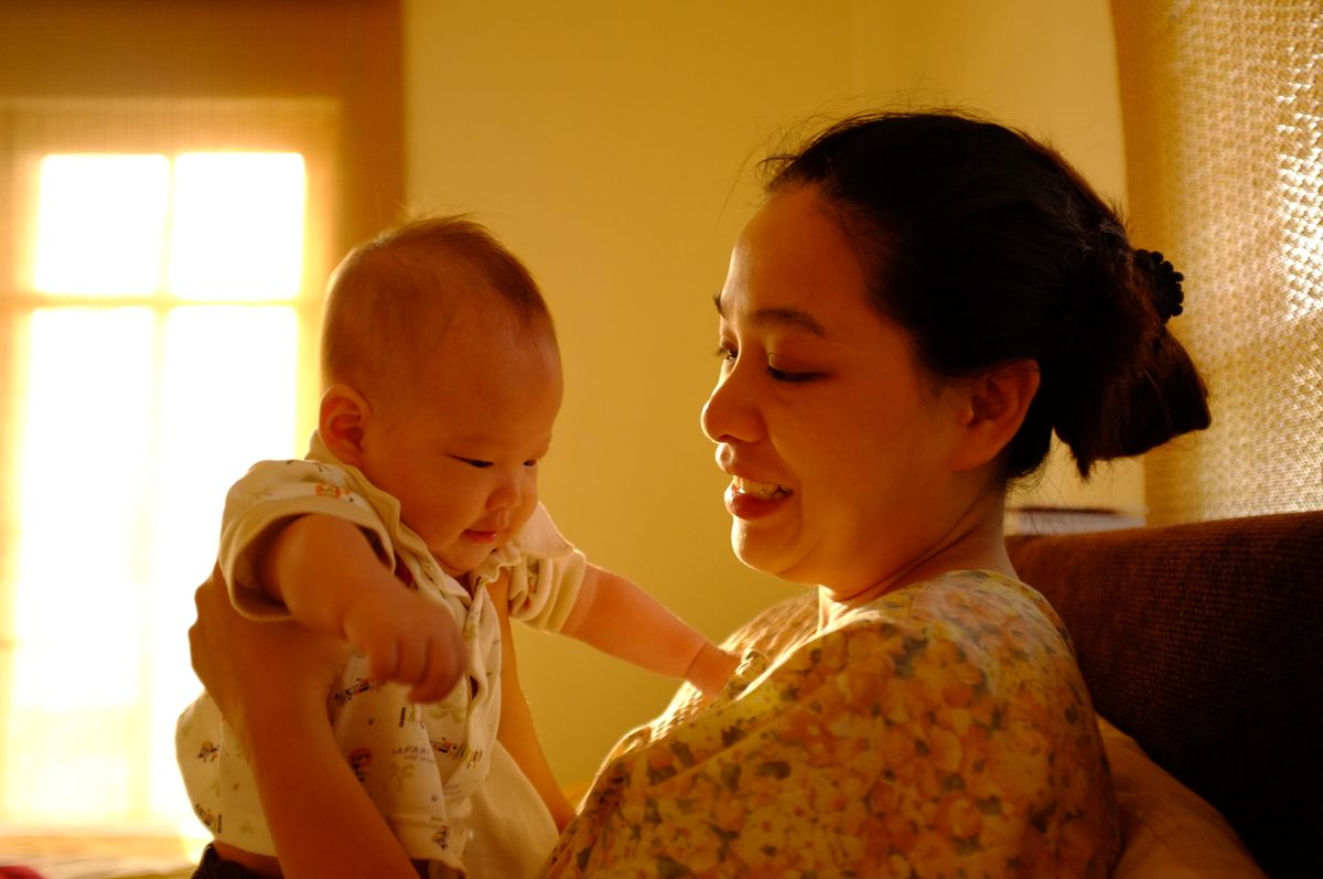 Mother holding her baby near a bright window at home