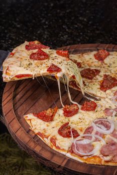 Delicious pepperoni pizza slice with onions and cheese on a rustic wooden board.