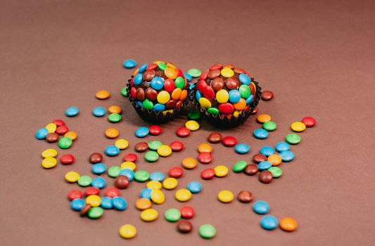 Delicious chocolate cupcakes topped with vibrant candy sprinkles on a brown background.