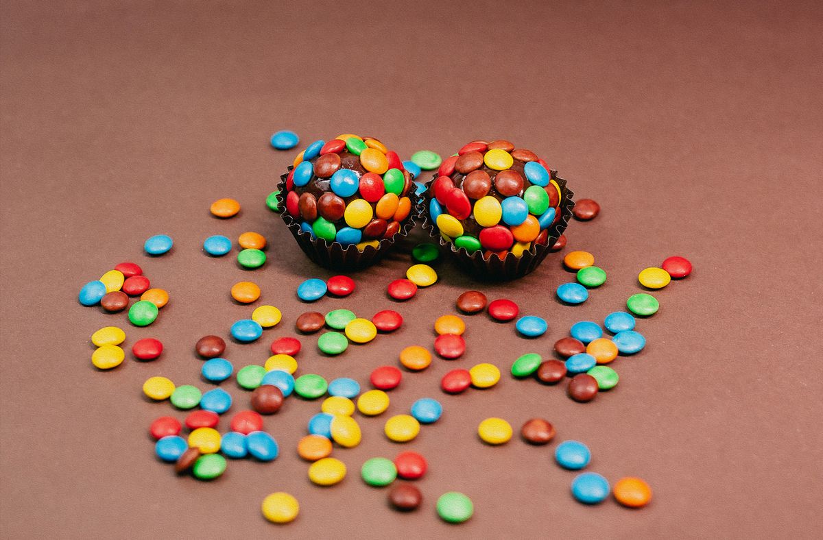 Delicious chocolate cupcakes topped with vibrant candy sprinkles on a brown background.