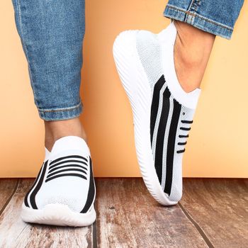 Trendy black and white slip-on sneakers paired with denim jeans, showcasing casual fashion.（イメージ）