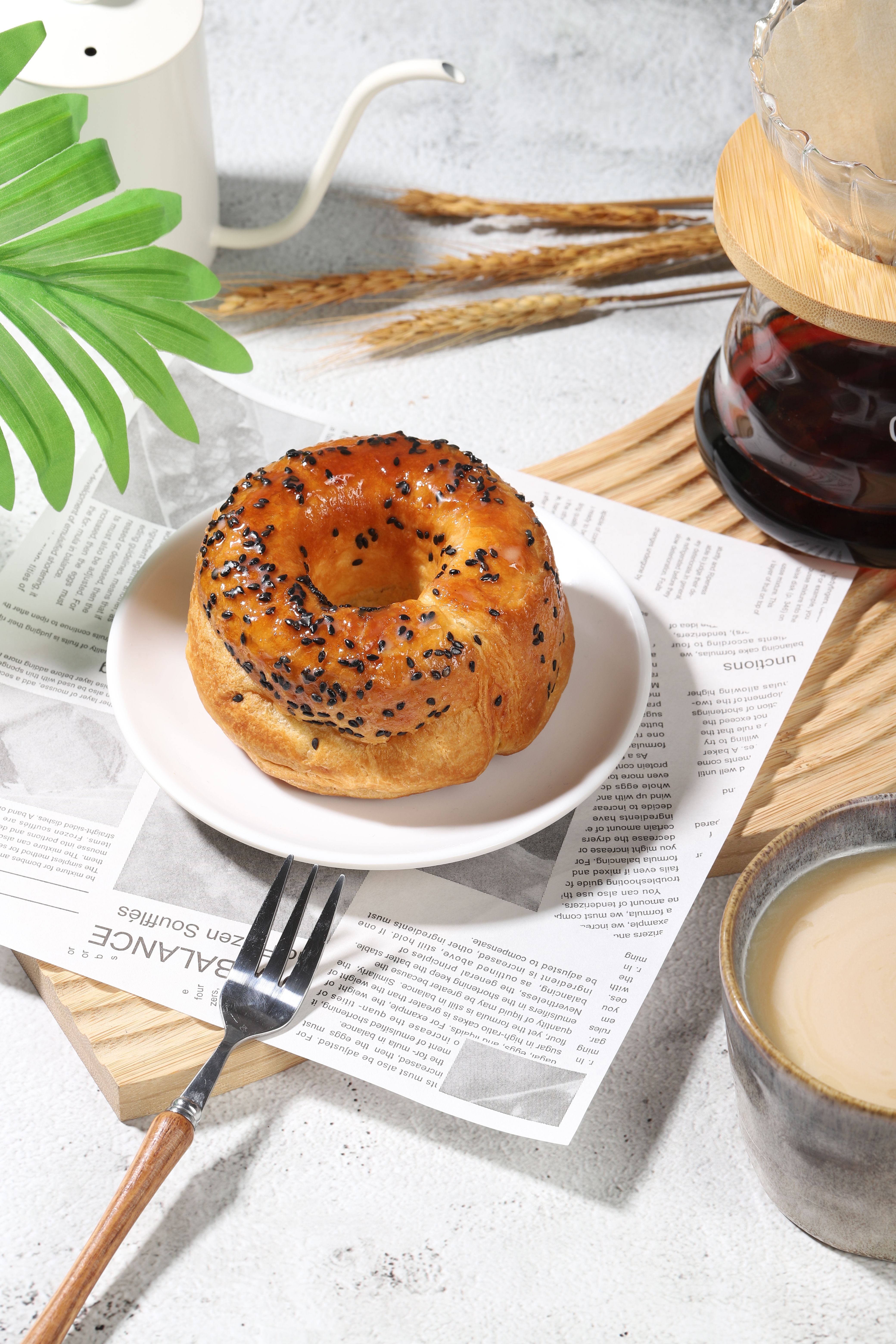 A freshly baked bagel with sesame seeds on a plate, paired with coffee, perfect for breakfast.