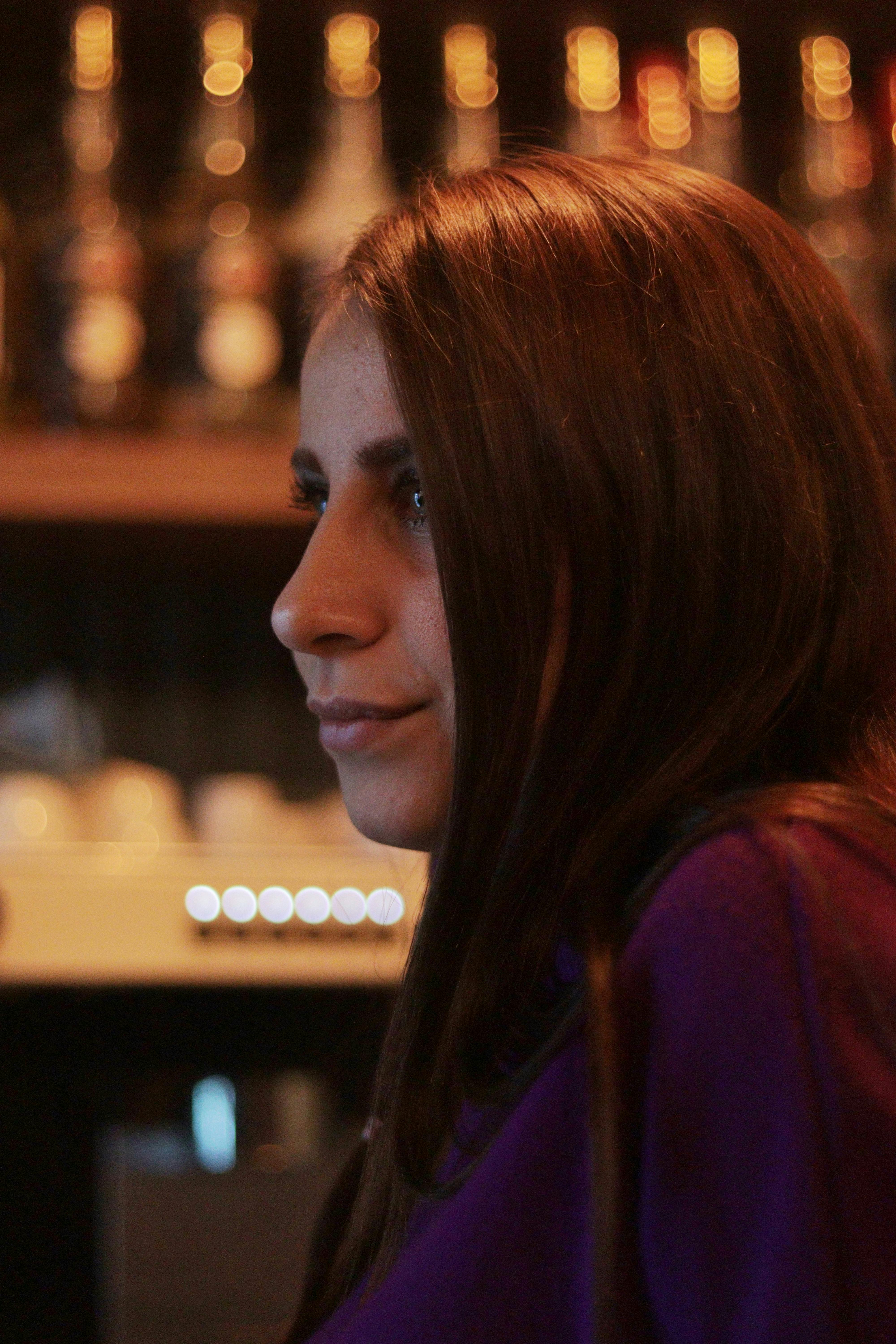 Side profile of a smiling brunette woman in a cozy bar ambiance.