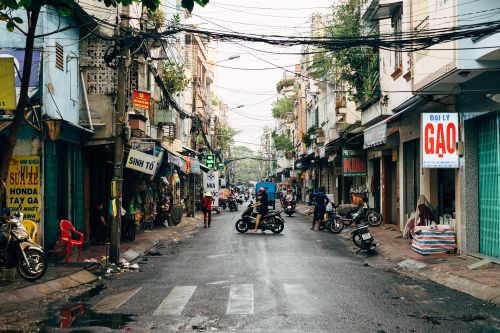 Free Bustling urban street scene in Ho Chi Minh City, Vietnam with motorbikes and local shops. Stock Photo