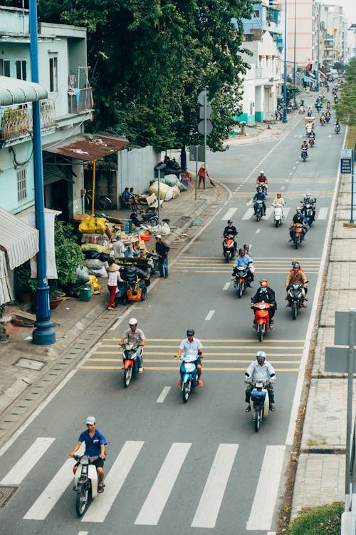 A group of people riding motorcycles down a city street