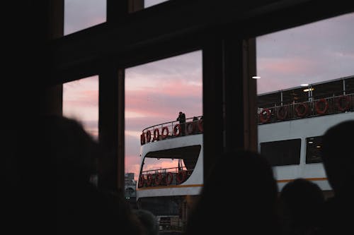 Person on Ferry Deck in Evening Seen Through Windows
