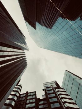 Dramatic view of London's modern skyscrapers reaching into a cloudy sky.