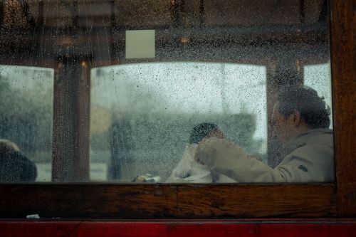 Free A man on a rainy day sitting inside public transport, gazing out of a rain-dotted window. Stock Photo