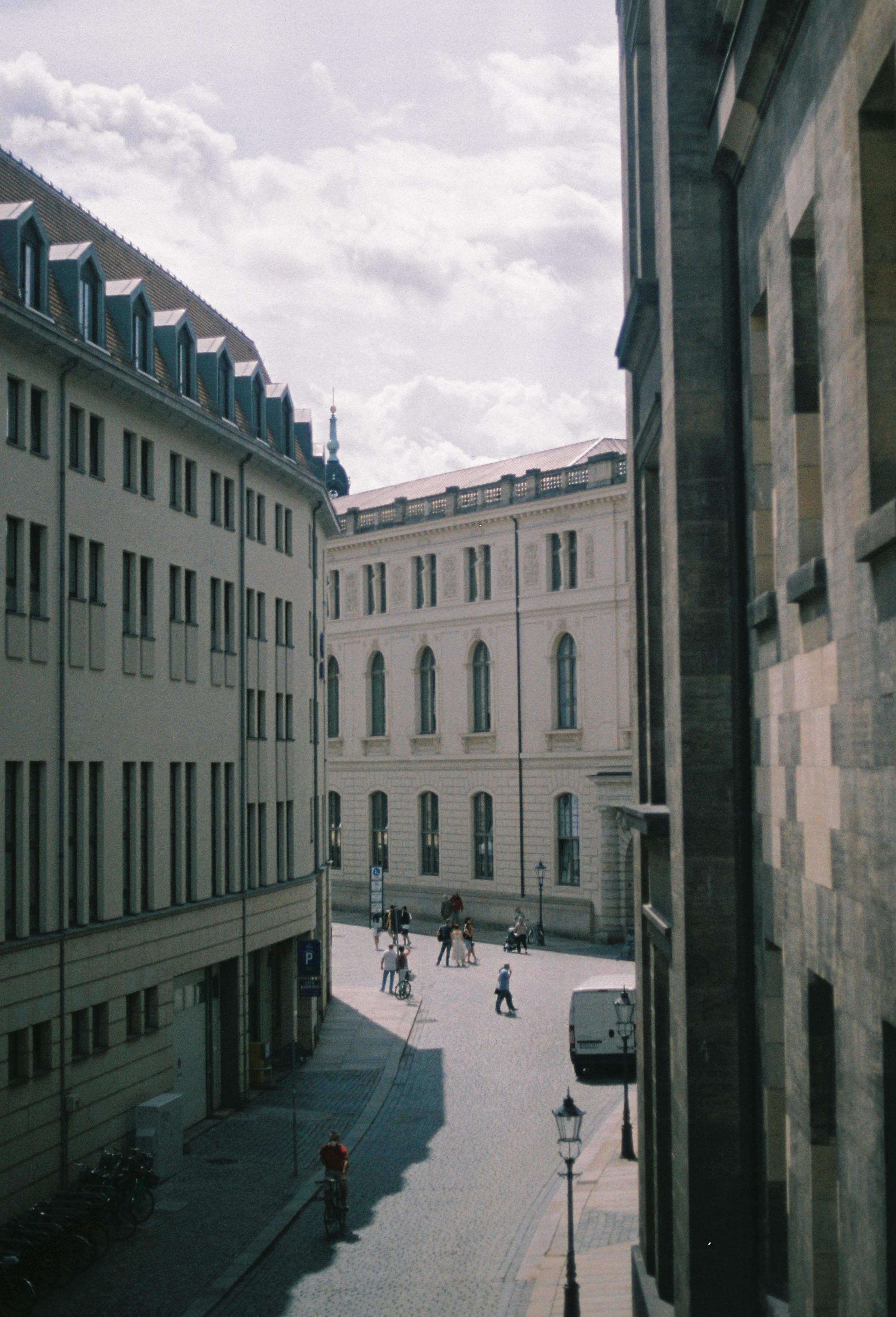 Cobblestone street in Dresden with historic architecture and few pedestrians.