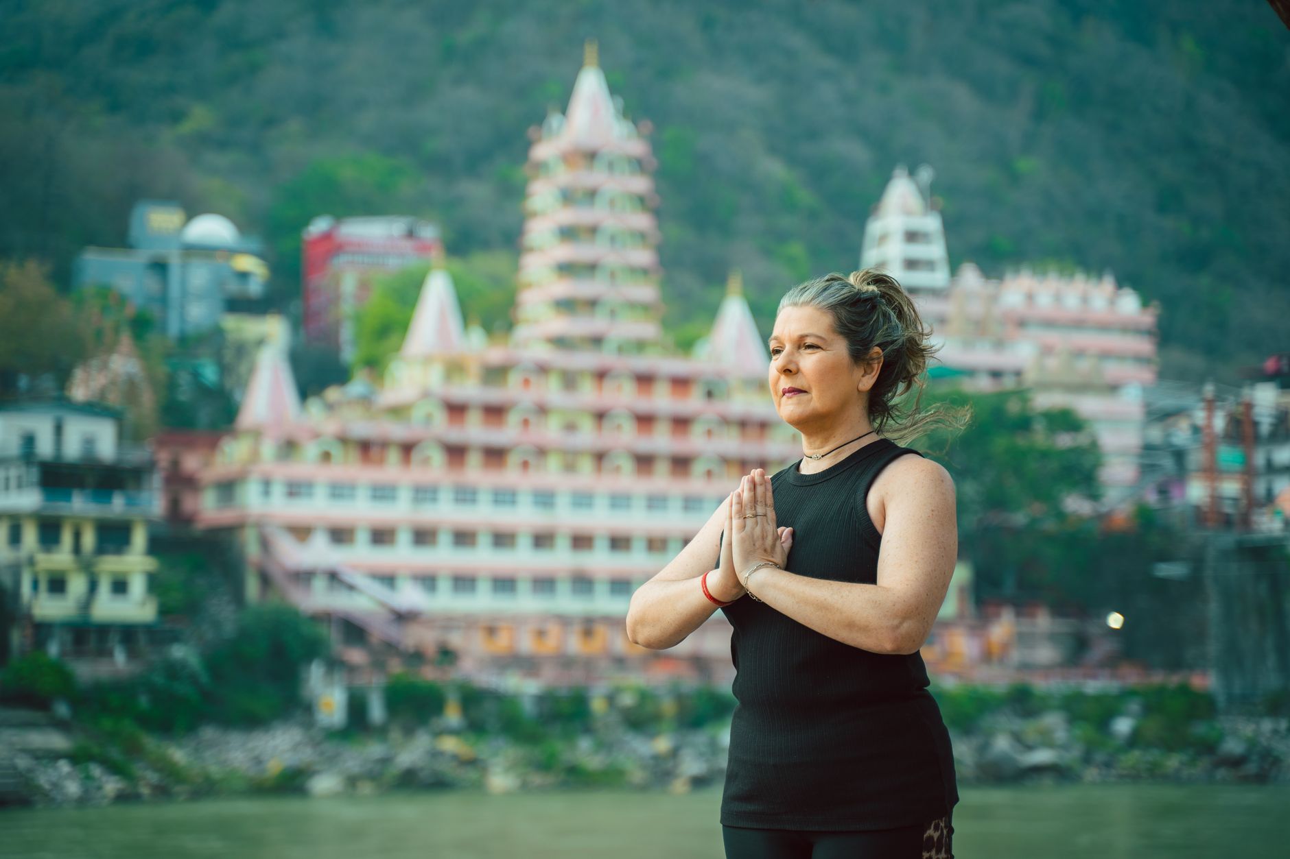 A woman doing yoga near the iconic Tera Manzil Temple in Rishikesh, India.