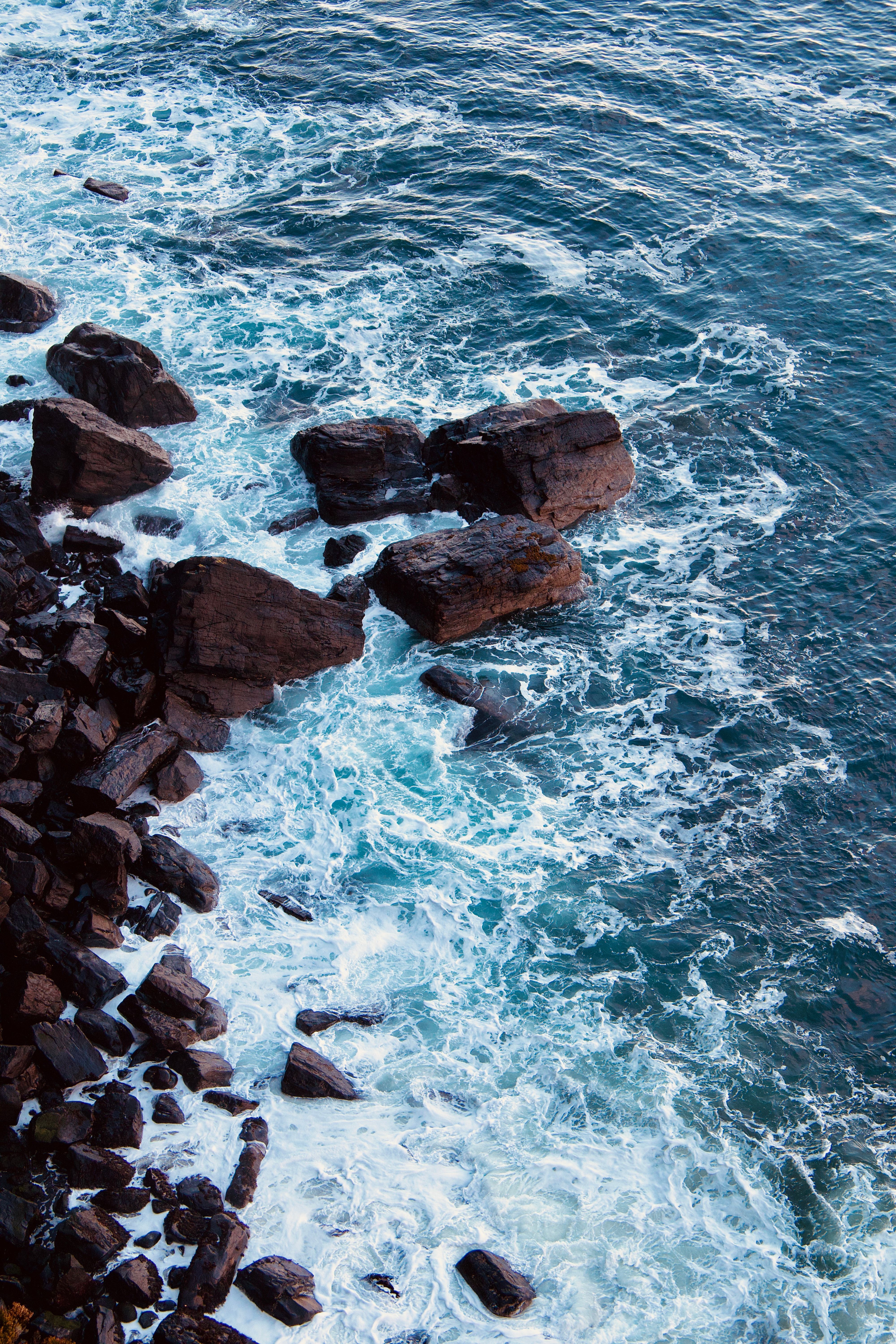 A view of the ocean from above with rocks and waves · Free Stock Photo