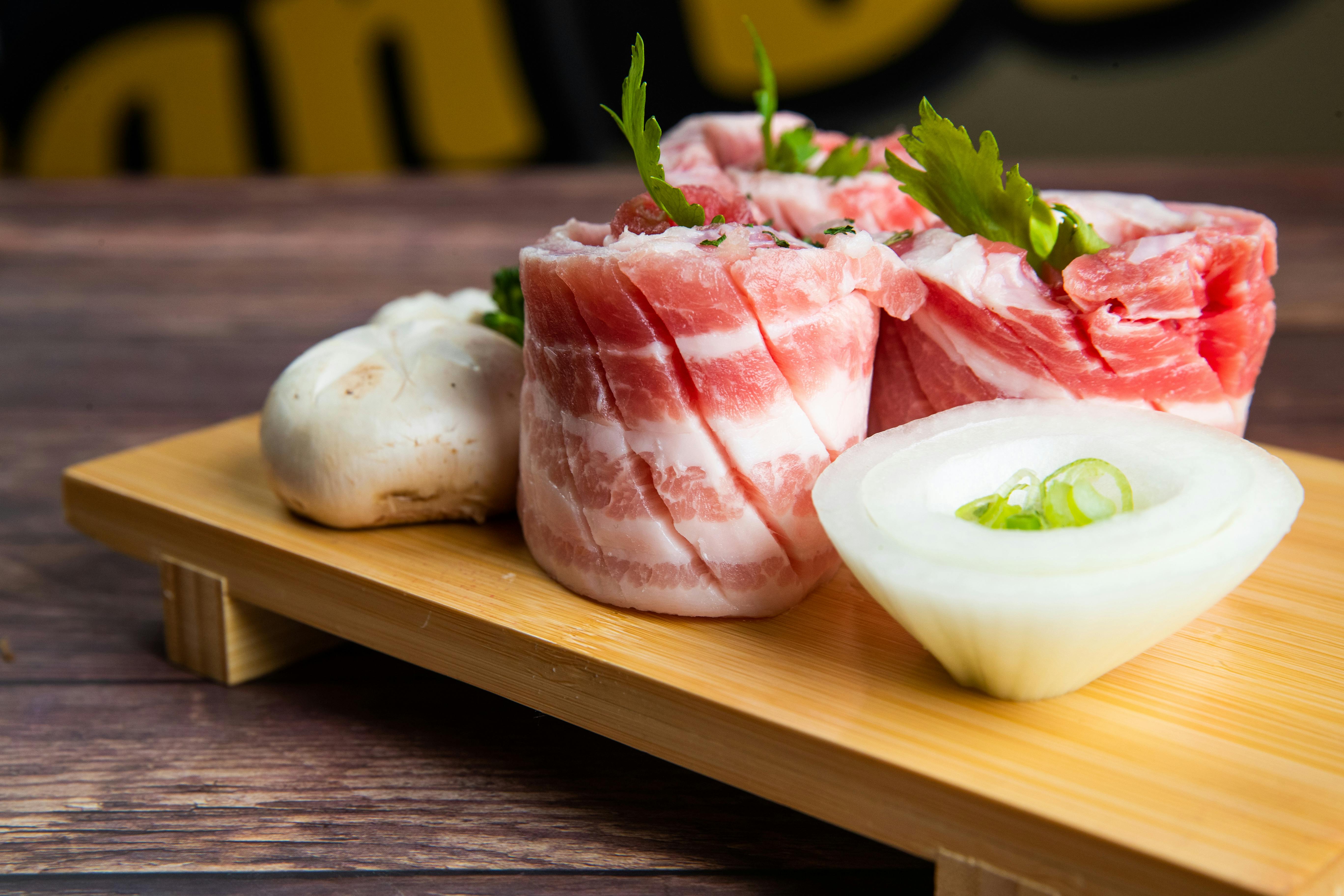 Raw beef rolls with onion and mushroom on wooden board, ready for cooking.