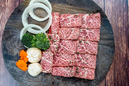 Sliced raw Wagyu beef with vegetables artfully arranged on a wooden platter for a gourmet dining experience.