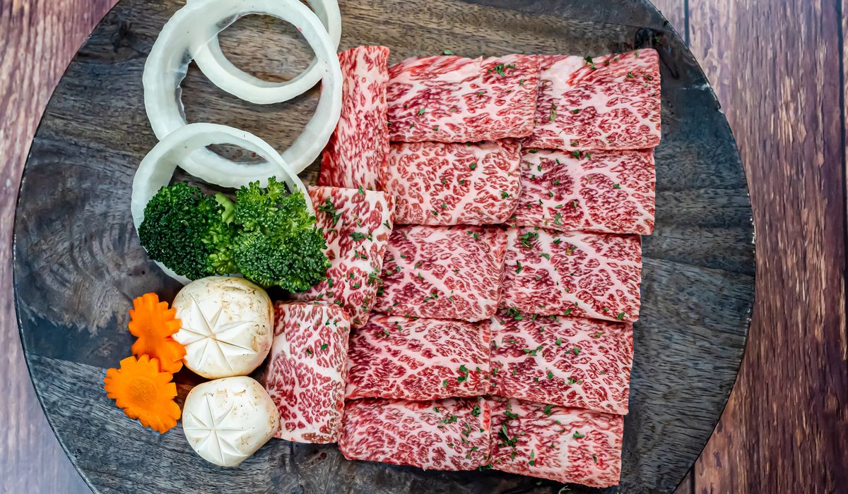 Sliced raw Wagyu beef with vegetables showing the dense white marbling of A5-grade Japanese beef