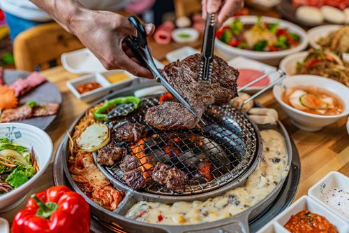 Free Close-up of grilling beef with scissors at a vibrant Korean BBQ dinner table. Stock Photo
