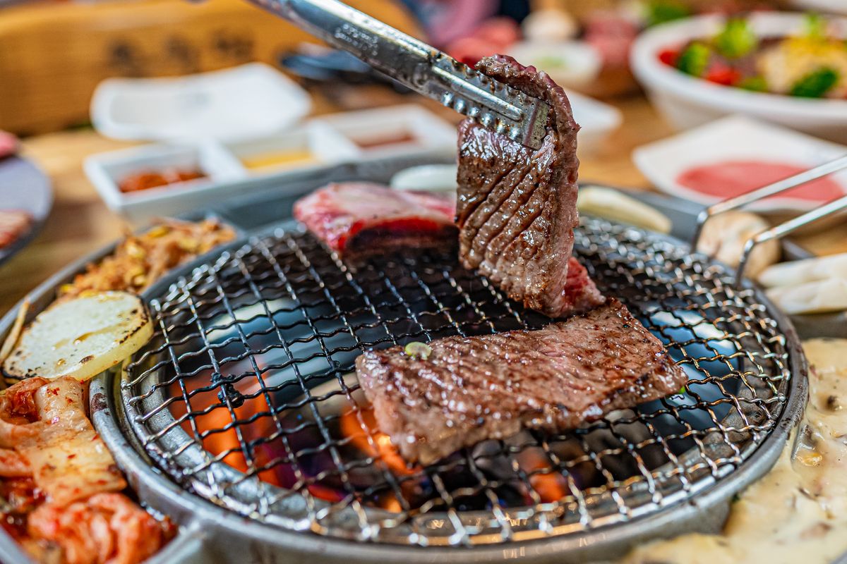 A Korean barbecue table with grilled meat, rice, kimchi, and side dishes.