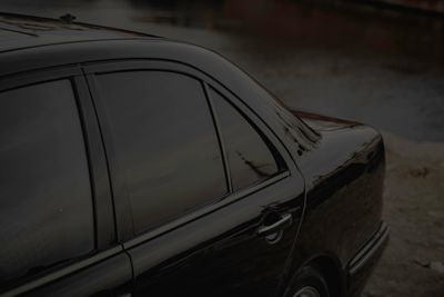 Black car with tinted windows by a riverbank