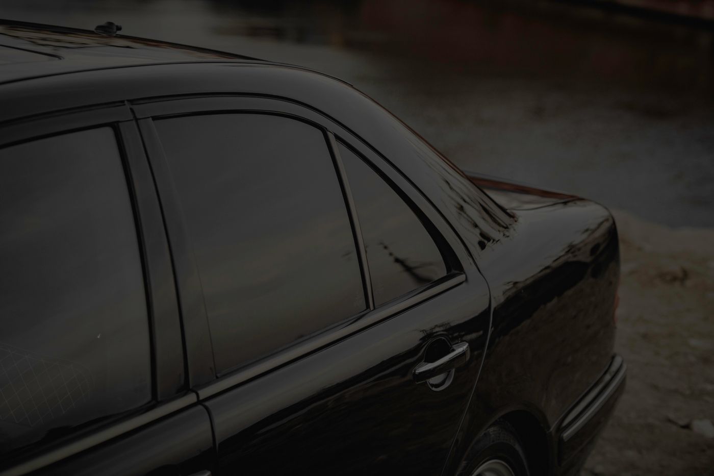 Black sedan with dark ceramic window tint installed at a Houston window tinting shop