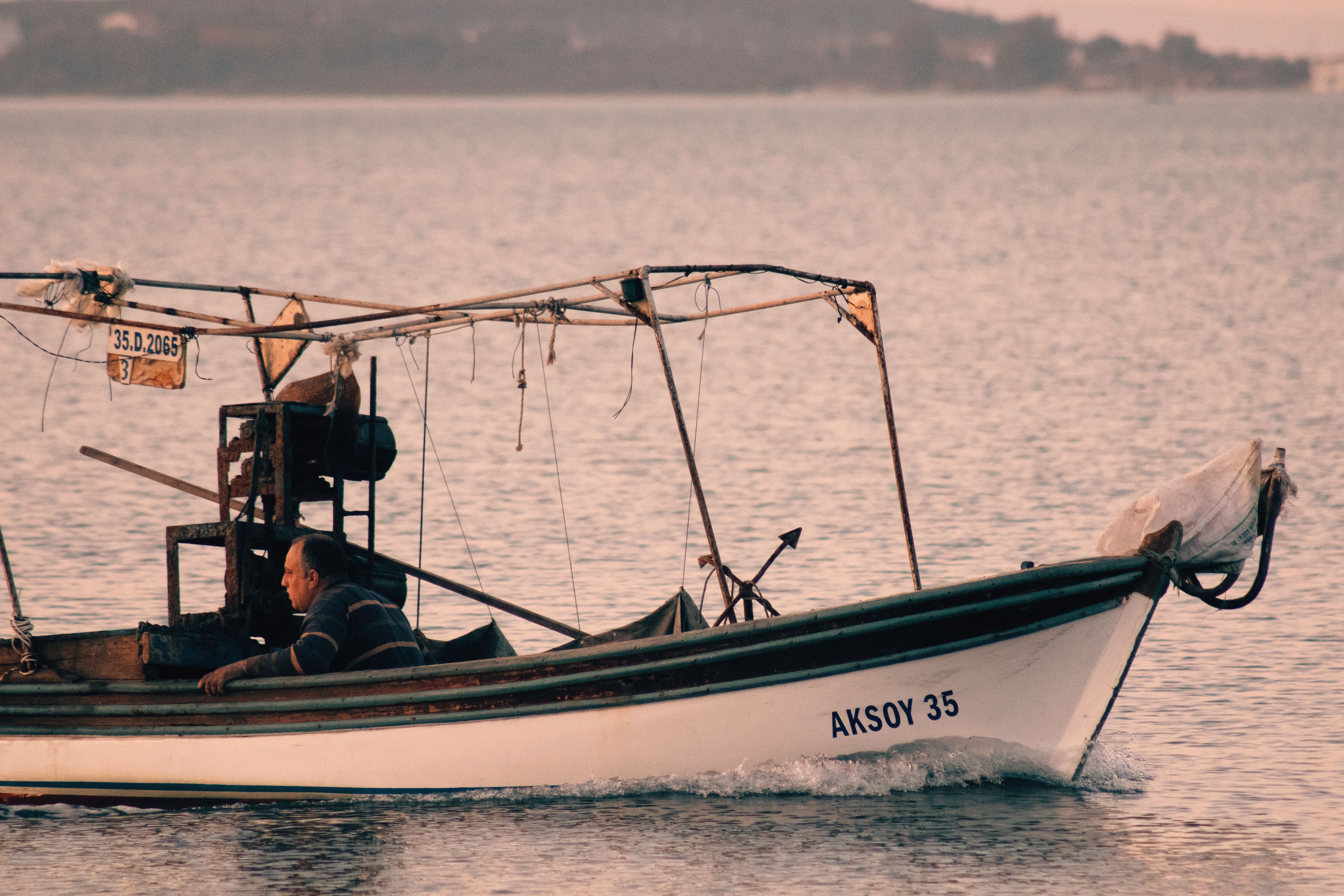 A fisherman works on a traditional fishing boat in Urla, Türkiye's serene waters.