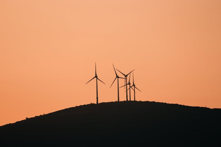 Wind Turbines And Hill Silhouette At Sunset